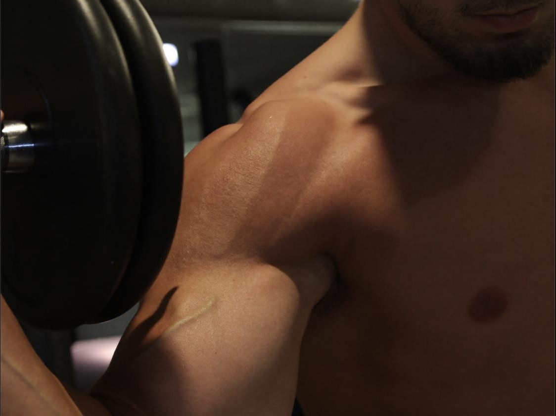 Close-up of a shoulder and arm pressing a dumbbell overhead